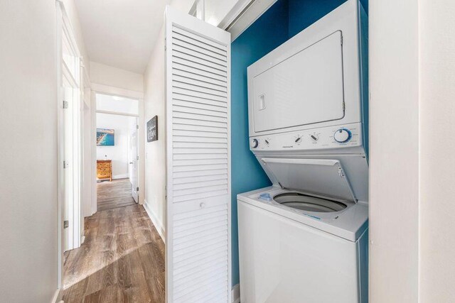 clothes washing area featuring stacked washing maching and dryer and light hardwood / wood-style flooring