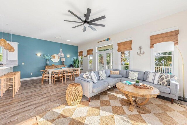 living room featuring ceiling fan with notable chandelier and light wood-type flooring