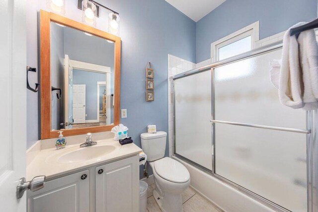 full bathroom featuring shower / bath combination with glass door, vanity, toilet, and tile patterned flooring