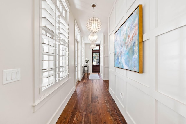 corridor with dark hardwood / wood-style flooring and a chandelier