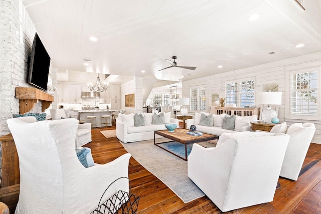 living room with ceiling fan with notable chandelier and dark hardwood / wood-style floors