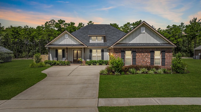 craftsman-style home featuring brick siding, board and batten siding, a yard, and roof with shingles