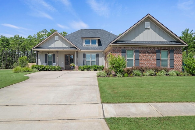 craftsman-style home with brick siding, board and batten siding, a shingled roof, and a front yard