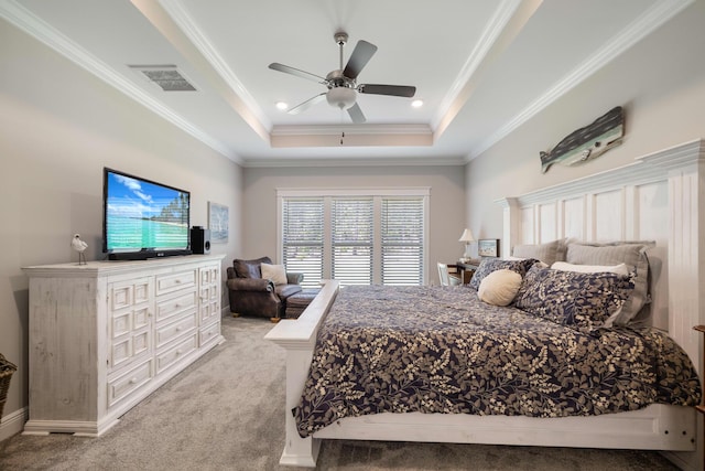 bedroom featuring visible vents, ornamental molding, a ceiling fan, a tray ceiling, and light colored carpet