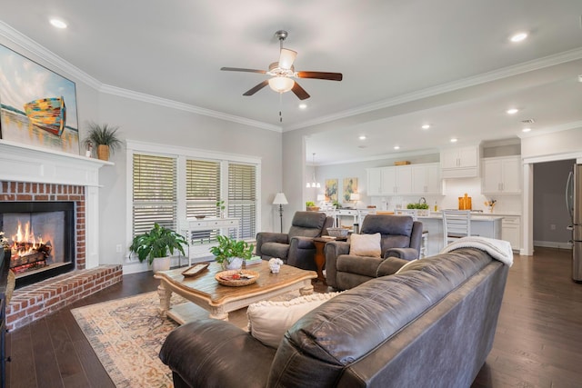 living room featuring recessed lighting, a brick fireplace, dark wood-style flooring, and crown molding