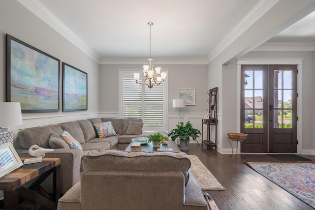 living room with a notable chandelier, dark wood-type flooring, ornamental molding, and wainscoting