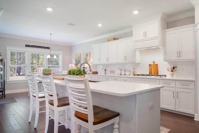 kitchen with dark wood finished floors, light countertops, gas cooktop, and ornamental molding