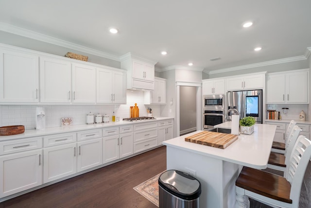 kitchen with a breakfast bar, stainless steel appliances, white cabinets, light countertops, and dark wood-style flooring