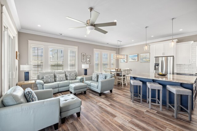 living room with crown molding, wood-type flooring, and ceiling fan