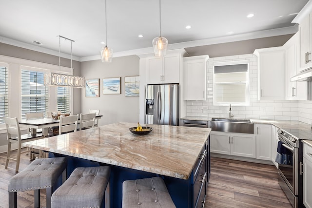 kitchen featuring backsplash, stainless steel appliances, a kitchen island, sink, and dark hardwood / wood-style floors