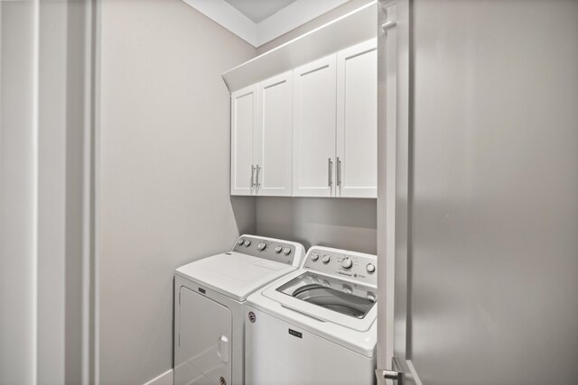 clothes washing area with cabinets and washing machine and clothes dryer