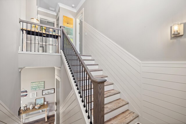 stairway with ornamental molding, hardwood / wood-style flooring, and wood walls