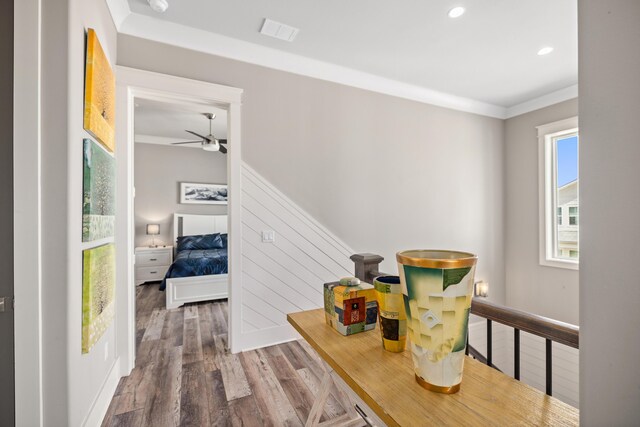 interior space with wood-type flooring, ornamental molding, and ceiling fan