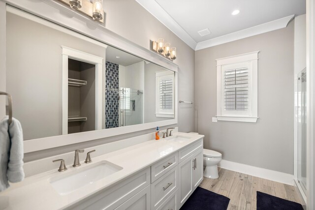 bathroom with toilet, a shower with door, crown molding, vanity, and hardwood / wood-style flooring