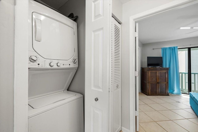 laundry area featuring stacked washer / drying machine and light tile patterned flooring