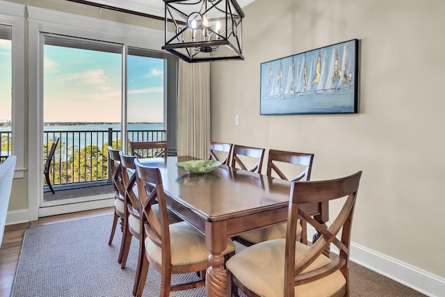 dining space with hardwood / wood-style flooring, a water view, and a chandelier