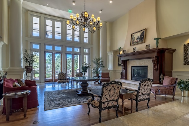 living room featuring a large fireplace, a high ceiling, a chandelier, and light hardwood / wood-style floors