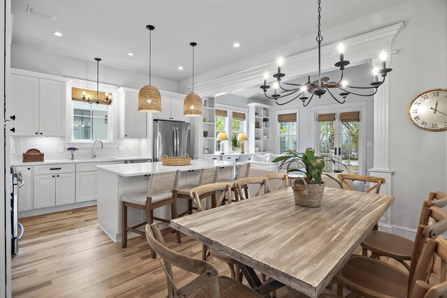 dining room featuring an inviting chandelier, sink, and light wood-type flooring