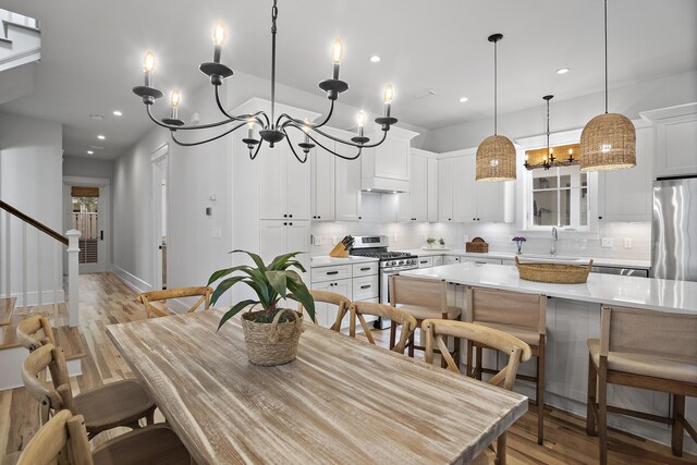 dining room with a notable chandelier, sink, and light wood-type flooring