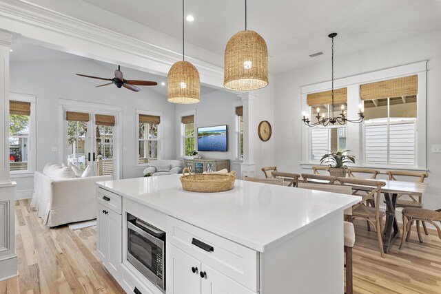 kitchen featuring stainless steel microwave, a wealth of natural light, and decorative light fixtures