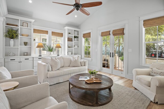 living room with light hardwood / wood-style floors, french doors, high vaulted ceiling, and ceiling fan