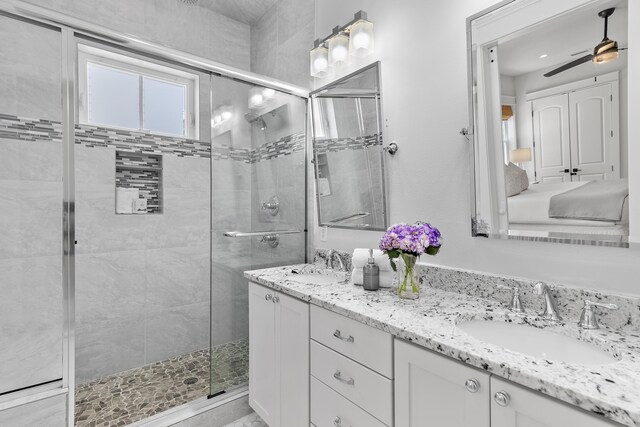 bathroom with vanity, ceiling fan, and walk in shower