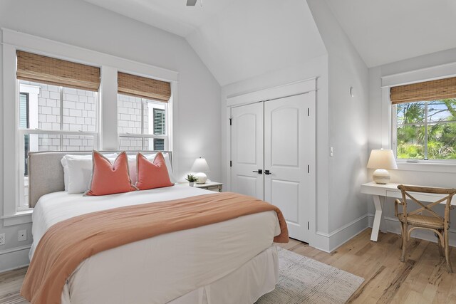 bedroom with light hardwood / wood-style floors, a closet, lofted ceiling, and ceiling fan