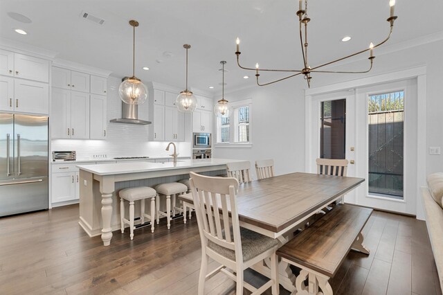 dining space featuring an inviting chandelier, plenty of natural light, dark hardwood / wood-style floors, and crown molding