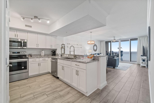 kitchen with white cabinets, stainless steel appliances, kitchen peninsula, and sink