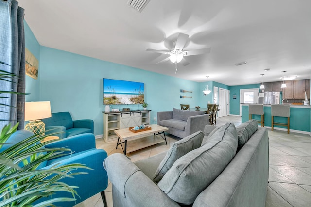 living room with light tile patterned floors, baseboards, visible vents, and ceiling fan