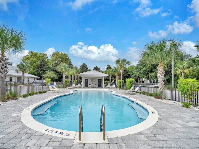 community pool with a patio area and fence