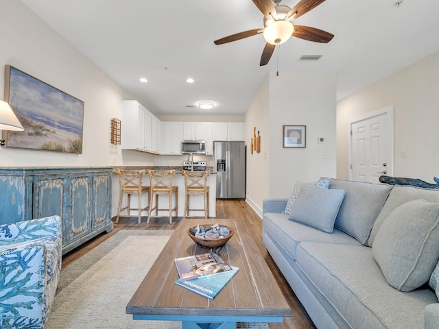 living room featuring a ceiling fan, baseboards, visible vents, recessed lighting, and light wood-type flooring