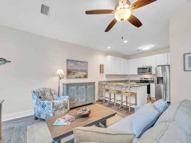 living area featuring visible vents, baseboards, light wood-type flooring, recessed lighting, and a ceiling fan