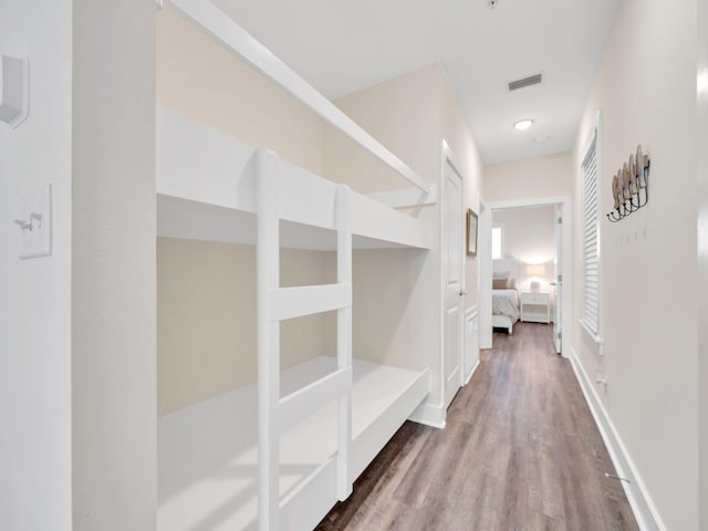 corridor featuring visible vents, baseboards, and wood finished floors