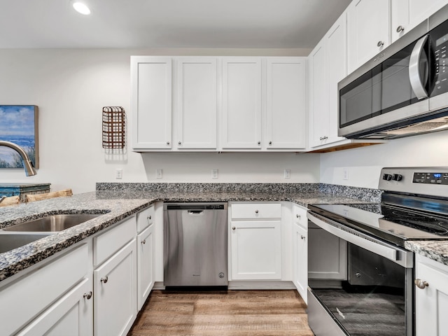 kitchen featuring a sink, light wood-style floors, appliances with stainless steel finishes, and white cabinets