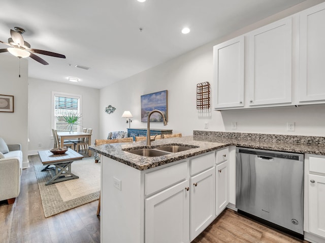 kitchen featuring visible vents, a peninsula, a sink, dishwasher, and light wood-type flooring