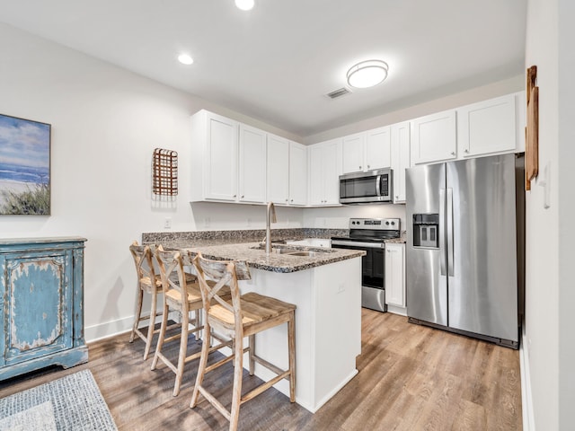 kitchen with visible vents, a sink, a kitchen breakfast bar, appliances with stainless steel finishes, and a peninsula