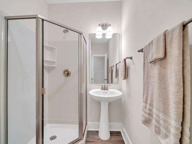 bathroom featuring an inviting chandelier, a shower stall, wood finished floors, and baseboards