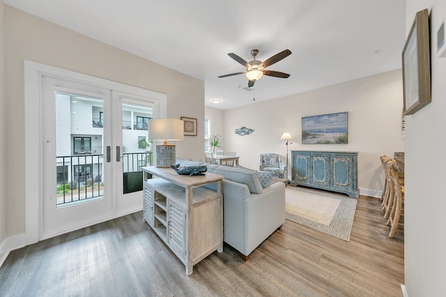 living area with ceiling fan, french doors, light wood-type flooring, and baseboards