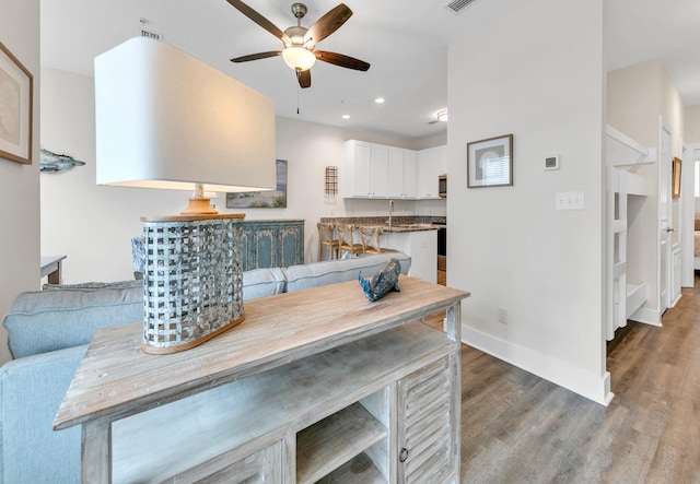 dining space with visible vents, baseboards, wood finished floors, and a ceiling fan