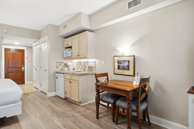 kitchen featuring tasteful backsplash, sink, white appliances, and light wood-type flooring