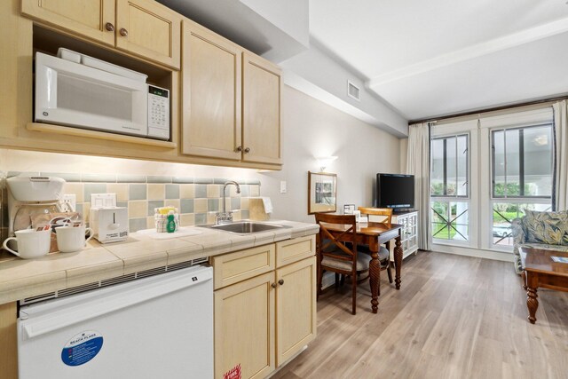 kitchen with sink, white appliances, decorative backsplash, tile countertops, and light wood-type flooring