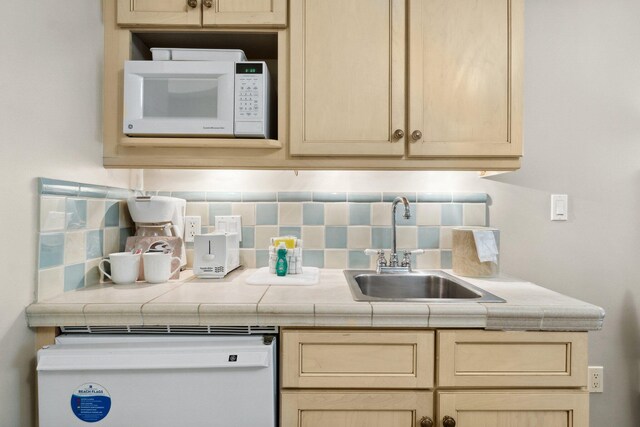 kitchen with sink, light brown cabinets, and backsplash