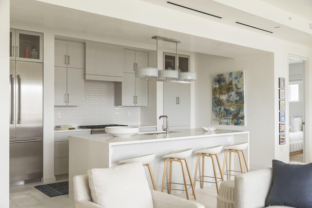 kitchen with pendant lighting, sink, tasteful backsplash, gray cabinets, and appliances with stainless steel finishes