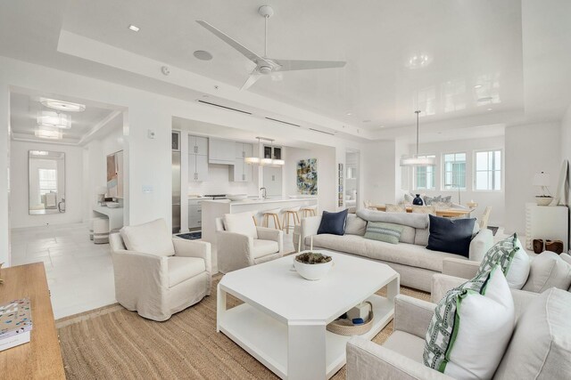 living room with ceiling fan, a raised ceiling, and sink