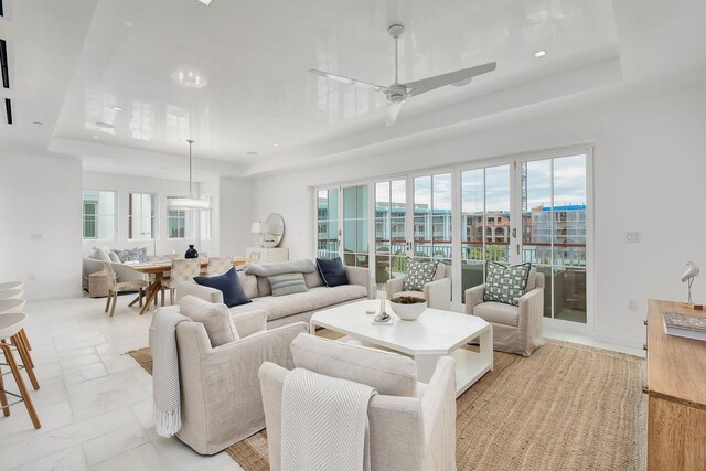 living room featuring ceiling fan and a tray ceiling