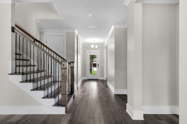 foyer featuring dark wood-type flooring, a chandelier, and crown molding