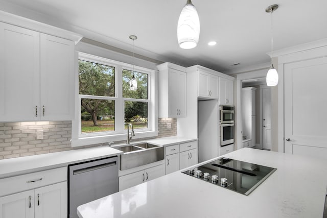 kitchen with appliances with stainless steel finishes, white cabinetry, and hanging light fixtures