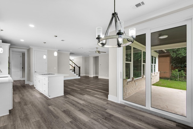 kitchen with white cabinets, hanging light fixtures, a center island, ceiling fan with notable chandelier, and dark wood-type flooring