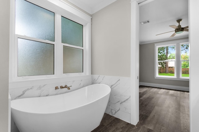 bathroom featuring a tub, crown molding, wood-type flooring, ceiling fan, and tile walls